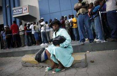 A woman sits in front a people lining up in a bank in Port-au-Prince, January 26, 2010. Haiti needs at least five to 10 years of reconstruction help after its people were "bloodied, martyred and ruined" by the devastating earthquake this month, Prime Minister Jean-Max Bellerive said on Monday. REUTERS/Jorge Silva