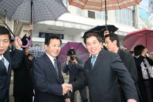 Kang Chel Su (2nd L), vice president of the Korea International Travel Company of the Democratic People's Republic of Korea (DPRK), shakes hands with Vice Director of the Chinese Travel Bureau Zhu Shanzhong (1st R) when welcoming the first tourist party from China to DPRK at the airport of Pyongyang, capital of DPRK, April 12, 2010. (Xinhua/Gao Ronghao)