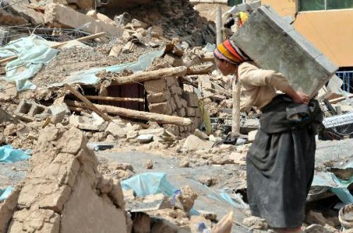 A woman collects her belongs in Gyegu Town, the quake-hit Tibetan Autonomous Prefecture of Yushu, in northwest China's Qinghai Province, April 17, 2010. The 7.1-magnitude earthquake that struck Yushu of Qinghai Province, left 1,484 dead and 312 still missing, and about 100,000 people were relocated. (Xinhua/Liu Siyang)