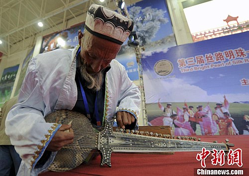 圖為展館現場，一位老人正在調試自己的樂器。劉新 攝