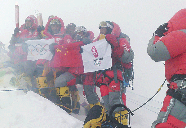 2008年奧運聖火首次登頂珠峰，火炬手歡慶勝利，展示中國國旗、奧運五環旗（阿旺羅布攝）