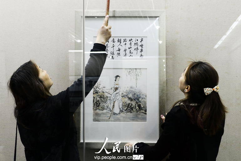 兩名工作人員正從展廊裏取下一幅被藏家收購的國畫作品。