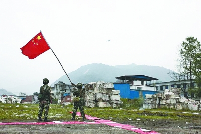 兩名戰士在寶興縣靈關鎮揮舞國旗引導救援直升機。 新華社圖