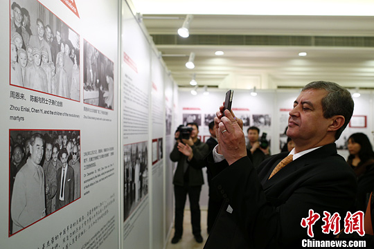 圖為阿爾及利亞駐中國大使哈桑納•拉貝希用手機拍攝展板上周恩來總理的照片。中新社發 富田 攝