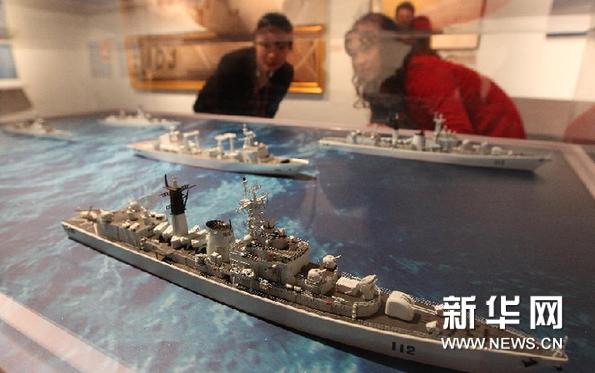  12月25日，工作人員（左）在上海中國航海博物館的預展上向參觀者介紹部分護航艦艇模型。新華網圖片 裴鑫 攝