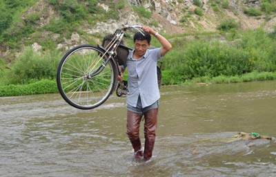 宋祥扛著自行車過河