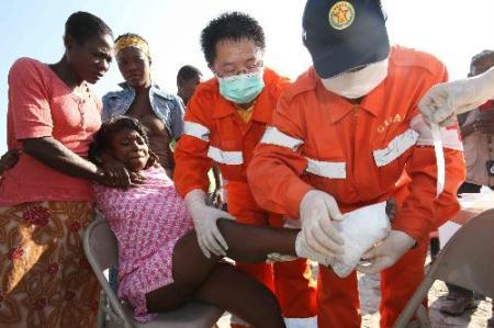 Medical workers of China International Search and Rescue Team (CISAR) bind up the wounded foot for a girl in Port-au-Prince, Haiti, Jan. 18, 2010. Members of CISAR have made all-out effort to offer medical services to Haitian peopel since the huge quake occured. (Xinhua/Yuan Man)