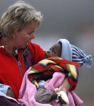 A woman believed to be from a Dutch adoption association carries two of the 106 children from a Dutch relief flight arriving in the Netherlands from Port-au-Prince, in Eindhoven January 21, 2010. REUTERS/Jerry Lampen