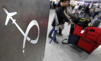 Passengers walk with a cart past a logo of Athens' International airport in Athens April 19, 2010. REUTERS/Yiorgos Karahalis