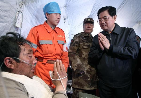 Chinese President Hu Jintao (1st R) talks to an injured man during his visit to those injured in the quake receiving treatment at a stadium in the Tibetan Autonomous Prefecture of Yushu, northwest China Qinghai Province, April 18, 2010. Hu arrived in Yushu Sunday morning to direct relief work. (Xinhua/Lan Hongguang)