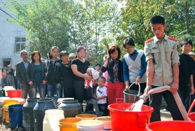 A firefighter fills up containers with clean water for drought-hit residents in Shangluoyuan village in Leping city, east China's Jiangxi province, October 24, 2009. Lingering drought continues to play havoc in southern and eastern China, stunting rice crops, lowering water levels in reservoirs and leaving hundreds of thousands of people short of drinking water, Xinhua News Agency reported.[CFP]