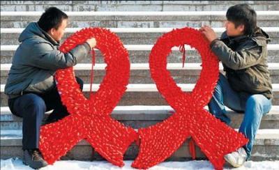 University students prepare intricate red ribbons on a street during an HIV/AIDS awareness rally ahead of World AIDS Day in Shenyang, Liaoning province, Sunday. China has reported 319,877 cases of AIDS patients and people living with HIV, and 49,845 deaths, as of Oct 31. (Photo source: chinadaily.com.cn)