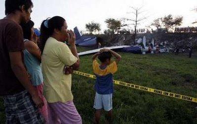 Filipino villagers look at the wreckage of a Russian cargo plane Antonov 12BP, operated by Pacific East Asia Cargo Airline, that crashed in a rice paddy in Mexico, Pampanga in northern Philippines April 22, 2010. Three crew members survived, while three others were killed in the crash, according to police investigators. REUTERS/Erik de Castro 