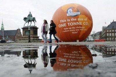 Two woman walk past a balloon with "This is the size of one tonne CO2" written on it near the City Hall of Copenhagen on December 9. 