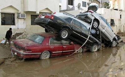 A man cleans outside a house next to a pile of cars in the Saudi coastal city of Jeddah in November 2009.(AFP/File)