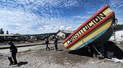 Local residents walk by a boat grounded by the earthquake and the ensuing tsunami in the fishing village of Constitucion, central Chile. (AFP/Martin Bernetti)