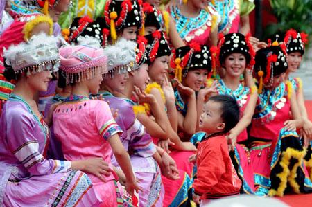 Performers greet a child after a performance during a "Harmonious Nanning, Joyous Green City" activity in Nanning, capital of southwest China's Guangxi Zhuang Autonomous Region, Oct. 22, 2009. During the 11th Nanning International Folk Song Arts Festival which kicked off here on Oct. 20, more than 200 artists from over 30 countries and regions and nearly 1000 Chinese artists will present their performance in 19 stages around Guangxi. As home to 28 ethnic groups, which are famed for their inherent love of singing and dancing, now Guangxi has become an international stage for folk songs and dances from all over the world.[Xinhua] 