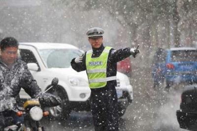 A police directs traffic in falling snow on a street in Yantai, east China's Shandong Province, Nov. 2, 2009. A cold front hit Yantai on Monday, bringing sharp drop of temperatures and snow in the city. (Xinhua Photo)