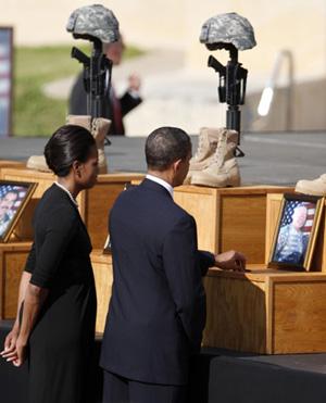 US President Barack Obama (R) places commemorative Commander in Chief challenge coins on the memorials of 13 victims of the November 5 shooting in Fort Hood, Texas, as first lady Michelle Obama accompanies him November 10, 2009. [Agencies]