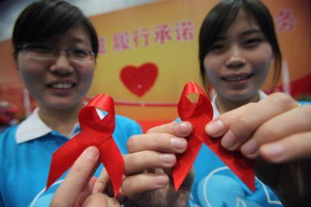 Volunteers show red ribbons during an AIDS awareness activity in Beijing, capital of China, Nov. 29, 2009. AIDS protection achievement show, AIDS protection volunteer recruitment and AIDS awareness publicity activity will be held during the AIDS protection volunteer week, which is from Nov. 29 to Dec. 5. (Xinhua/Chen Xiaogen)