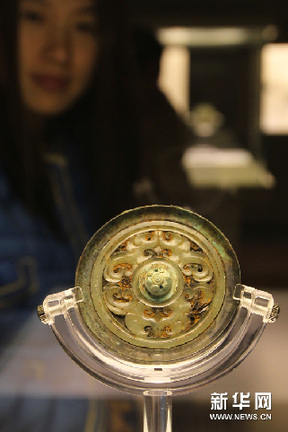 11月15日，一名觀眾在欣賞戰國時期的“嵌玉綠松石鈕變形龍紋鏡”。新華網圖片 任瓏 攝