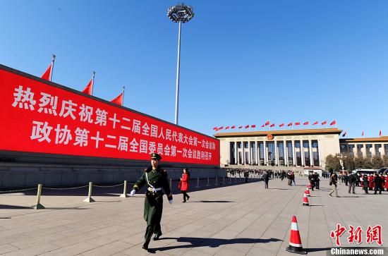 3月4日，北京晴空萬里，武警從北京天安門廣場大型顯示屏前走過。3月5日上午，十二屆全國人大一次會議將隆重開幕。中新社發 劉忠俊 攝