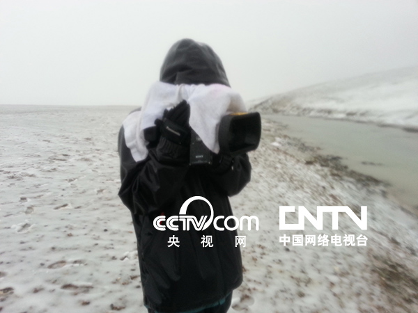 攝像陳鑑開用隨身攜帶的毛巾搭在攝像機上遮擋風雪，但他的衣服已經完全濕透
