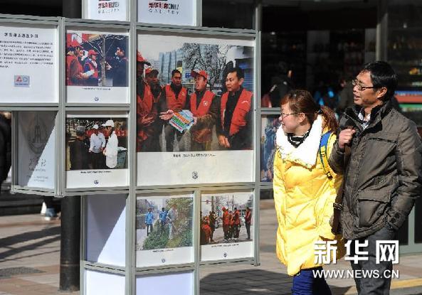  3月5日，遊客在北京王府井觀看首都學雷鋒志願服務示範站（崗）圖片展。新華網圖片  羅曉光 攝