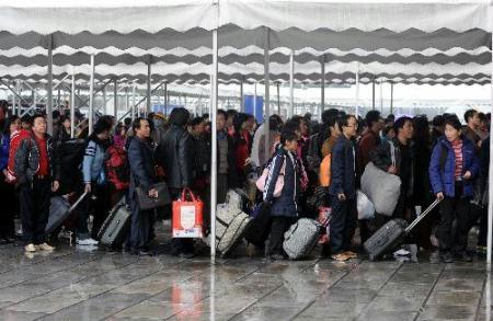 Passengers enter the railway station under a shelter against the rain in Guangzhou, south China's Guangdong Province, Feb. 7, 2010. In spite of a heavy rain, the Guangzhou Railway Station was estimated to transport 230,000 passengers on Saturday, 5,000 more than the peak day of last year. (Xinhua/Lu Hanxin) 