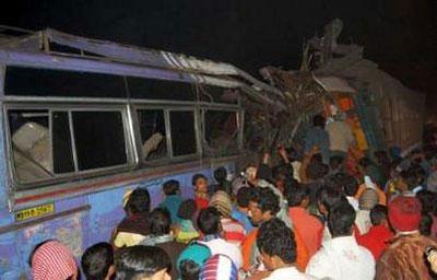 Onlookers and rescuers stand beside a bus and a truck trailer that collided on a highway at Kulgachia, about 50 km (31 miles) southwest of the eastern Indian city of Kolkata December 13, 2009.REUTERS/Stringer