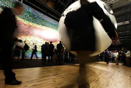 People walk past a globe at the venue of the United Nations Climate Change Conference in Copenhagen, capital of Denmark, December 19, 2009.(Xinhua/Xie Xiudong)