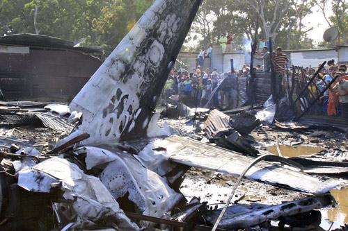 People gather around the scene where a L-39C plane crashed at a slum 300 meters away from the international airport Antonio Jose de Sucre in Cumana, capital of Venezuelan state of Sucre, March 21, 2010. The light plane crashed into three houses on Sunday killed at least 6 people and hurt 3. (Xinhua/Jose Guilarte)