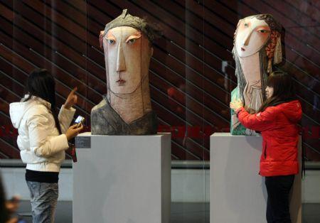 A visitor poses with a statue during the open day at the National Center for the Performing Arts (NCPA), or the National Grand Theater, in Beijing, capital of China, Dec. 22, 2009.  (Xinhua/Luo Xiaoguang)