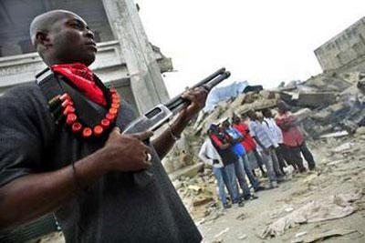 A private security guard stands outside a burning store in downtown Port-au-Prince January 19, 2010. REUTERS/Carlos Barria