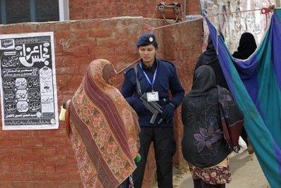 Shiite women walk past a policewoman standing guard at the entrance to the women's section of a mosque in Islamabad during Ashura. A suicide attack at a Shiite Muslim mosque in Pakistani-administered Kashmir killed five people and wounded dozens more, marking a bloody start to Ashura commemorations.(AFP/Behrouz Mehri)