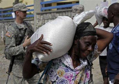 A woman smiles while carrying a sack of rice during a food distribution operation by an aid organization in Port-au-Prince, Sunday, Jan 31, 2010. (AP Photo/Ramon Espinosa)