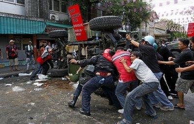 Anti-government demonstrators try to remove an abandoned Thai Army armored vehicle Sunday morning, April 11, 2010, in Bangkok, Thailand, near Democracy Monument. Savage clashes between protesters and Thai soldiers killed people before both sides retreated, no closer to ending a monthlong occupation of parts of the capital by demonstrators demanding new elections. (AP Photo/Vincent Yu) 