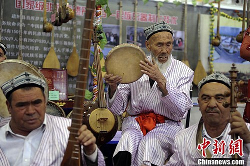 圖為博覽會現場一支民族樂隊正在演奏，其間一位打手鼓的老人陶醉在音樂中。劉新 攝