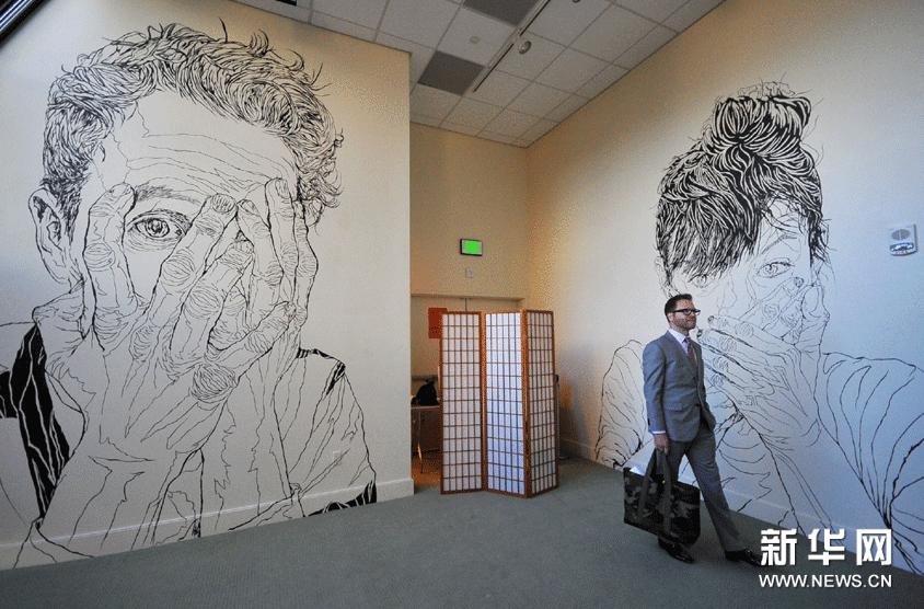 2月22日，在美國舊金山中華文化中心舉行的“水墨時刻”聯展媒體預展上，一名記者欣賞美國畫家喬納森•沃爾雷文的巨幅線描人像。