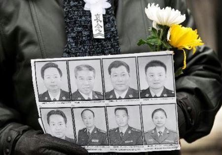 A mourner holding the portraits of eight peacekeeping police officers who were killed in the Haiti earthquake waits for the arrival of their coffins at the Babaoshan Revolutionary Cemetery in Beijing, Jan. 19, 2010. The coffins of the eight peacekeeping police officers are to be brought here on Tuesday. (Xinhua/Wang Jianhua)