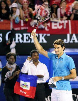 Roger Federer of Switzerland, right, waves to the crowd next to the representatives of Melbourne Haitian community, after an exhibition tennis match in Melbourne, Australia, Sunday Jan. 17, 2010. (AP Photo/Shuji Kajiyama)