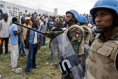 In this photo released by MINUSTAH, Peruvian UN peacekeepers secure the entrance of an industrial area during a distribution of food by humanitarian workers from Dominican Republic in Port-au-Prince, Tuesday, Jan. 19, 2010. (AP Photo/MINUSTAH, Marco Dormino)