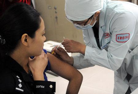 A policewoman receives the A/H1N1 influenza vaccination at a hospital in Shijiazhuang, capital of north China's Hebei Province, on Oct. 28, 2009. A vaccination program against the A/H1N1 virus is kicked off in the province on Wednesday. (Xinhua/Gong Zhihong)