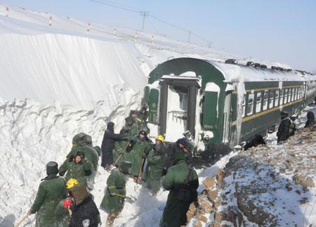 Soldiers clear snow that strands a train in Shangdu, north China's Inner Mongolia Autonomous Region, Jan. 4, 2010. Due to heavy snowfall on Sunday, several trains were delayed and some were stranded in remote areas in Inner Mongolia. Local government dispatched about 10,000 people including soldiers to the snow-affected areas to evacuate stranded passengers and clear snow on roads and railways. More than 1,400 stranded passengers were settled in the safe neighborhood in Shangdu by 14:00 Monday. (Xinhua/Tian Yu)