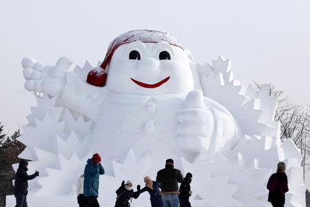 Tourists pose near a snow sculpture during the 26th Harbin International Ice and Snow Festival at a park in Harbin, Heilongjiang province, January 5, 2010.[Photo/Agencies]