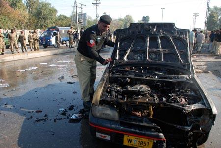 A member of security force inspects a damaged car at the blast scene in Peshawar, northwest Pakistan, on Nov. 19, 2009. A suicide bombing killed at least 16 people and injured 36 others in Peshawar on Thursday, officials and hospital sources said.(Xinhua/Umar Qayyum)