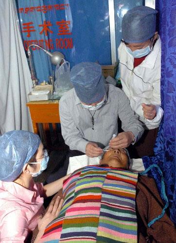 　　資料圖片：2005年7月18日，參加中華“健康快車”北京－－西藏光明行的眼科專家抵達西藏拉薩後，立即為西藏貧困白內障患者實施免費復明手術。圖為來自北京和香港的眼科專家為西藏那曲縣一位84歲的白內障患者進行手術前麻醉。