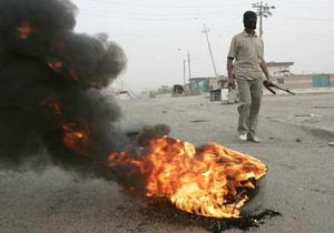 A fighter from the Mahdi Army militia stands guard near a burning tyre on a road in Baghdad's Sadr City March 26, 2008. Fourteen people were killed and more than 140 wounded in clashes between security forces and Shi'ite militants in Baghdad's Sadr City slum, a medical source said on Wednesday. (Xinhua/Reuters Photo)