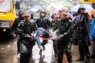 Rescuers carry the body of a victim at the Juyuan High School in Juyuan Town, Dujiangyan City, southwest China's Sichuan Province, May 13, 2008. Rescuers work against the rainy weather to search quake survivors on Tuesday. (Xinhua Photo)