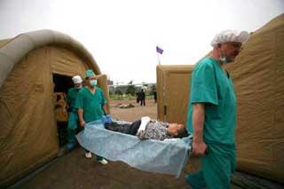 Two Russian surgeons shift an injured-citizen with stretcher to the inflatable wards after winding up the surgical operation, at Pengzhou, southwest China's Sichuan Province, May 21, 2008. The Russian medical team carried out surgical operations at the inflatable mobile hospital, comprising surgery rooms, patients' ward and other relevant facilities on Wednesday morning. (Xinhua Photo)